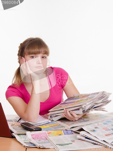 Image of Girl sitting with a pile of newspapers at table