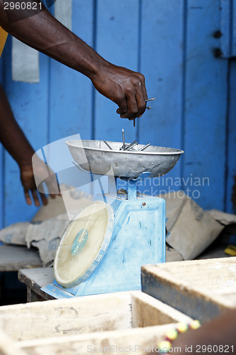 Image of African carpenter weighs nails on a scale 