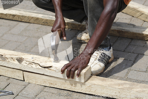 Image of African carpenter works with wood