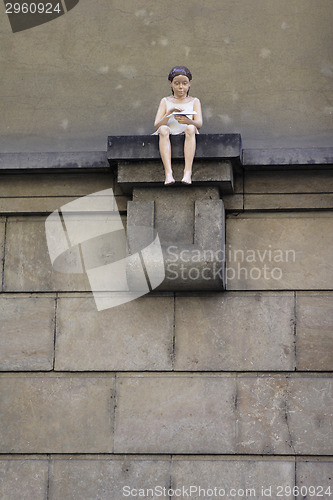 Image of Figure of a girl sitting on the house wall