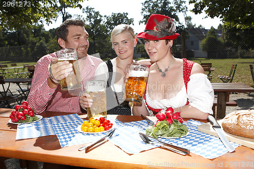 Image of Three Bavarians in traditional costumes sitting in a beer garden