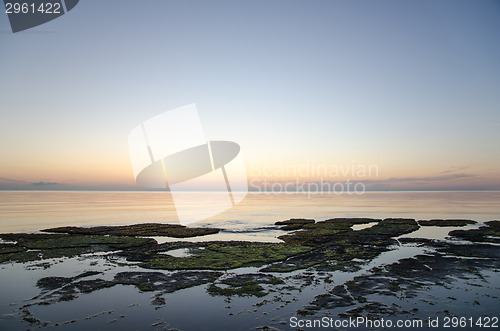 Image of Sunset at a flat rock coast