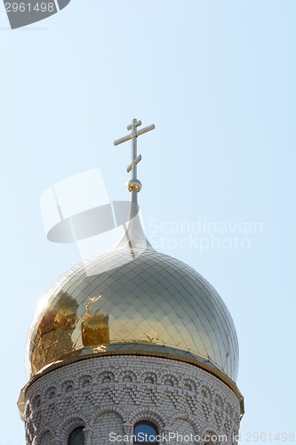 Image of Golden cupola and christian cross on church against blue sky