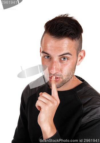 Image of Young man with finger on mouth.