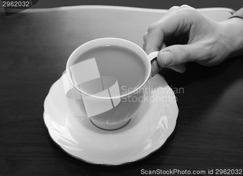 Image of Woman picking up a cup of tea from a table