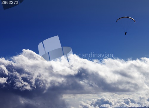 Image of Silhouette of paraglider and blue sunny sky