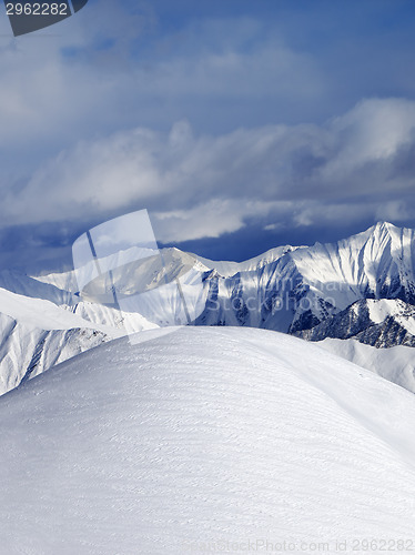 Image of Top of off piste snowy slope and cloudy mountains