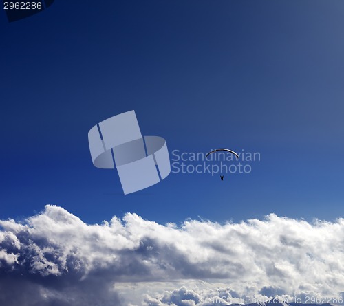 Image of Silhouette of paraglider and blue sunny sky