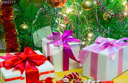 Image of Beautifully packed gift by Christmas and the decorated fir-tree.