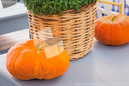 Image of Still life: two pumpkins and a wattled basket with greens.