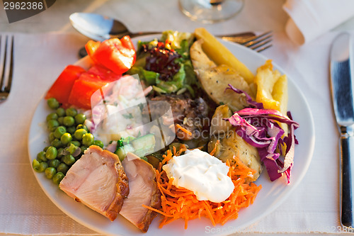 Image of Meat, fish and various vegetable garnish on a plate.