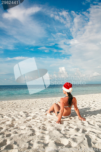 Image of Woman in santa hat on the beach