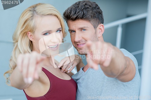 Image of Smiling attractive couple pointing at the camera