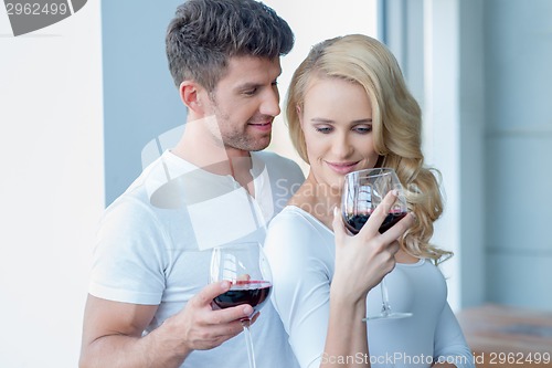 Image of Happy couple drinking red wine to celebrate