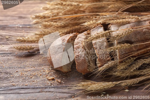 Image of Bread and wheat on wooden table, shallow DOF