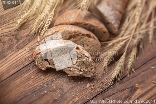 Image of Bread and wheat on wooden table, shallow DOF