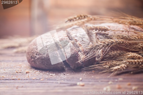 Image of Bread and wheat on wooden table, shallow DOF