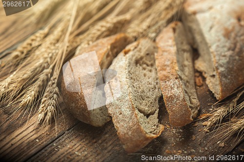 Image of Bread and wheat on wooden table, shallow DOF