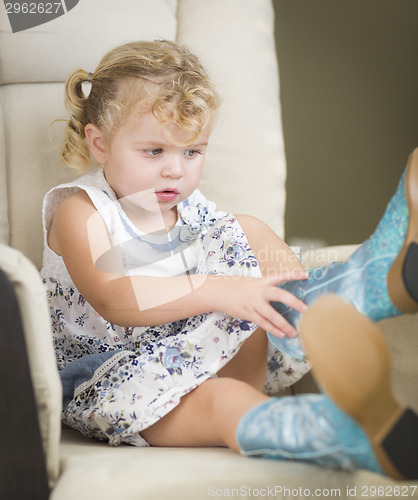 Image of Blonde Haired Blue Eyed Little Girl Putting on Cowboy Boots