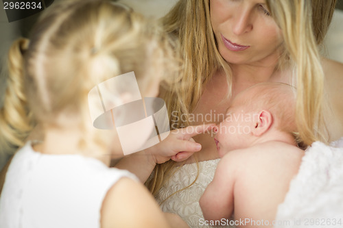 Image of Young Mother Holds Newborn Baby Girl as Young Sister Looks