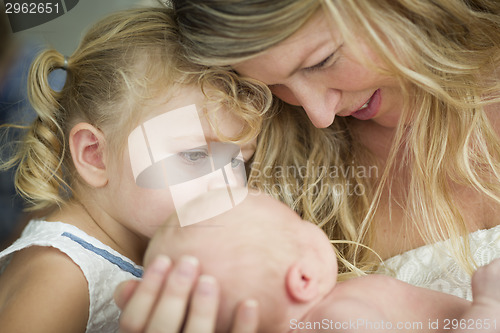 Image of Young Mother Holds Newborn Baby Girl as Young Sister Looks