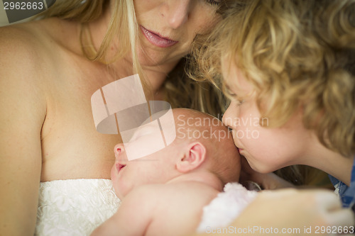 Image of Young Mother Holds Newborn Baby Girl as Brother Kisses Her