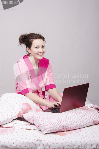 Image of The girl sat in bed with a laptop