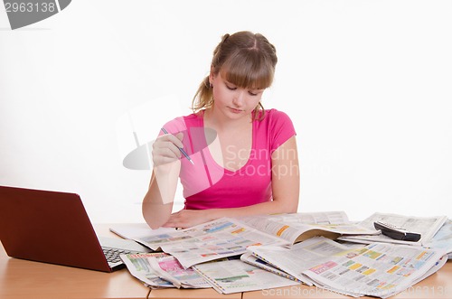 Image of Girl looking for the right ad in newspaper