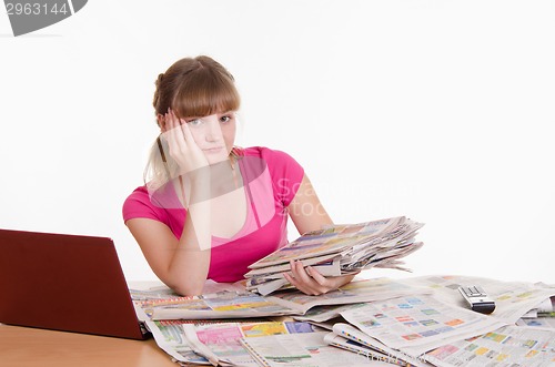 Image of Sad girl with a stack of newspapers