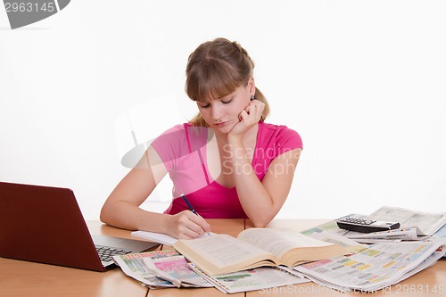 Image of The girl writes a phone number to notebook