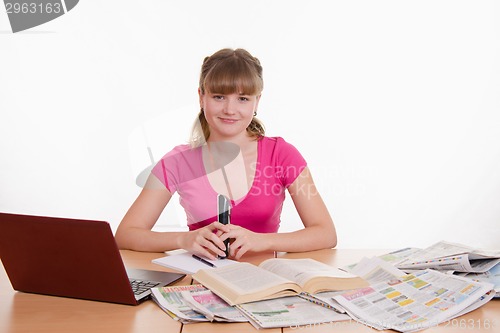 Image of Girl sitting at table with laptop and newspaper