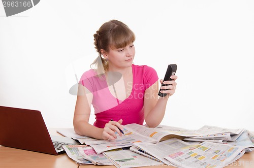 Image of Woman dials the phone number of ads