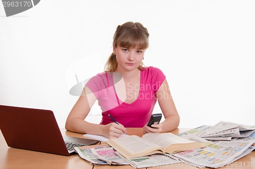 Image of The girl writes a phone number from directory to notebook