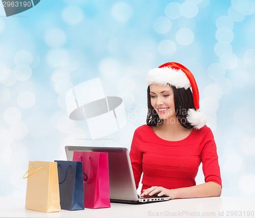 Image of smiling woman in santa hat with bags and laptop