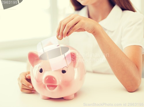 Image of smiling child putting coin into big piggy bank