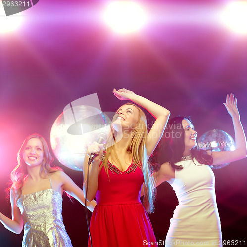 Image of three smiling women dancing and singing karaoke