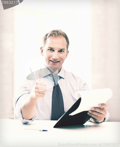 Image of businessman with papers showing thumbs up