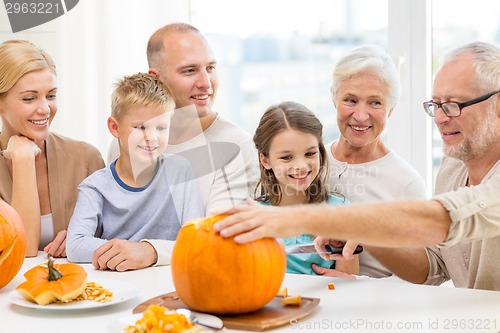 Image of happy family sitting with pumpkins at home