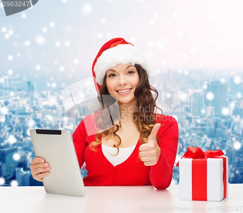 Image of smiling woman in santa hat with gift and tablet pc