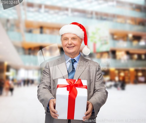 Image of smiling man in suit and santa helper hat with gift