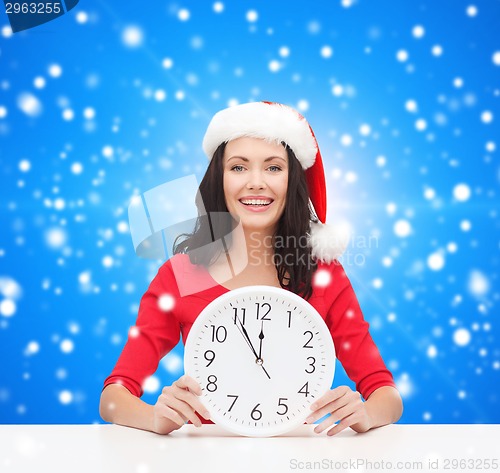 Image of smiling woman in santa helper hat with clock