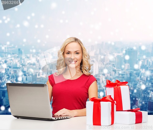 Image of smiling woman in red shirt with gifts and laptop
