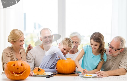 Image of happy family sitting with pumpkins at home