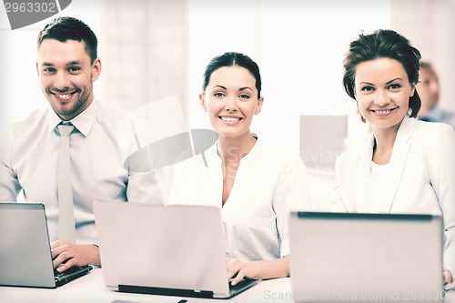 Image of group of people working with laptops in office