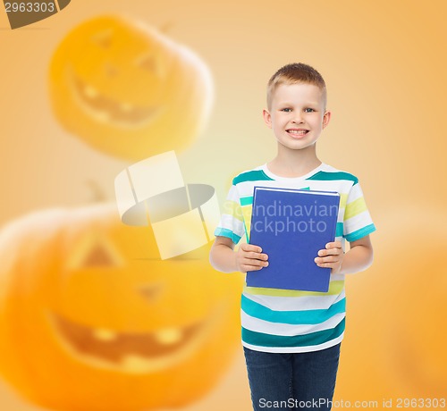 Image of smiling little student boy with blue book