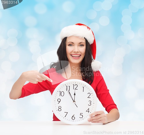 Image of smiling woman in santa helper hat with clock