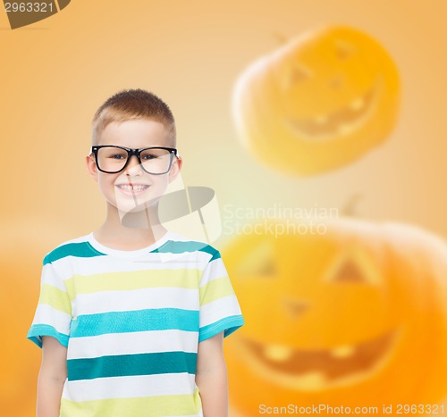 Image of smiling boy in glasses over pumpkins background