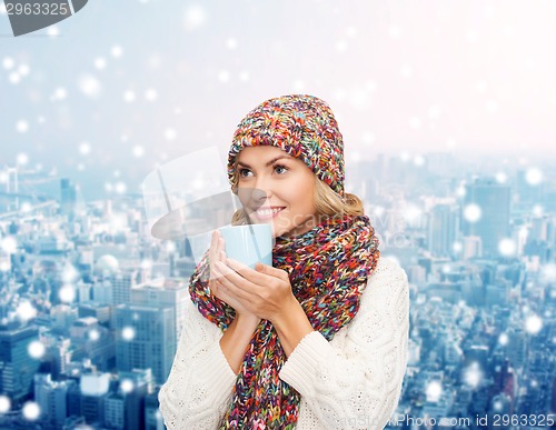 Image of smiling young woman in winter clothes with cup