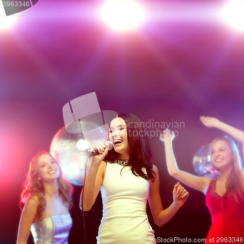 Image of three smiling women dancing and singing karaoke