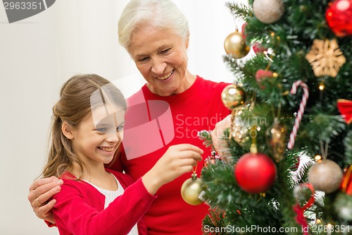 Image of smiling family decorating christmas tree at home